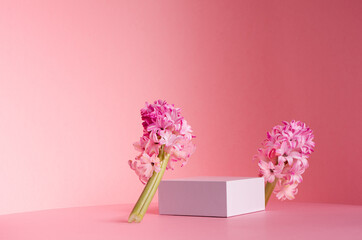 Delicate spring mock up for cosmetic and product display with white square podium, tender hyacinth flowers standing on pastel pink background.