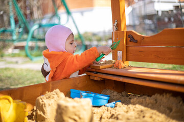 adorable toddler playing in the sandbox. cute child in fox pajamas plays in the sand. portrait of a happy baby