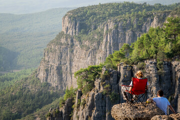A man sits on the edge of a cliff against the backdrop of a gorge. The Tazi Canyon is located in the northern part of the Koprulu Canyon National Park, close to the cemetery of the Gaziler Village.