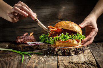 Tasty grilled homemade burgers with beef, tomato, cheese, bacon and lettuce on rustic wooden background. fast food and junk food concept