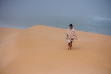 Fototapeta na wymiar Woman walking alone along sand dune