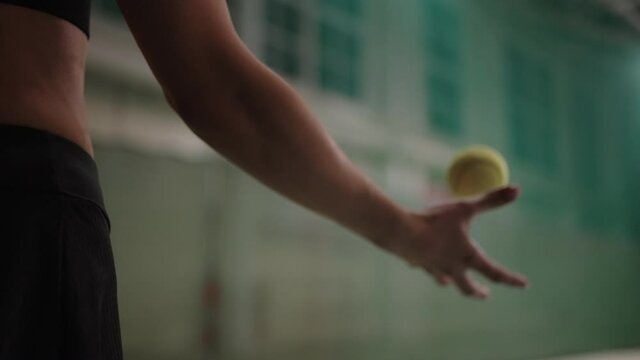 training of pro female tennis player, closeup of hand throwing ball up, preparing to serve, details on tennis court indoors