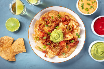 Mexican nachos, shot from above with a variety of dips and sauces