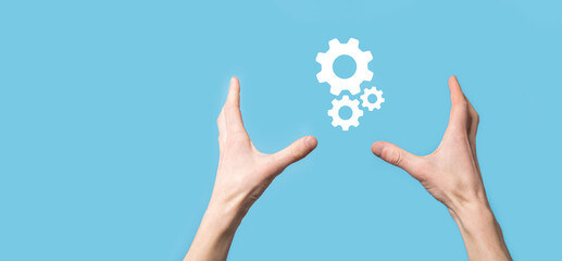 Male hand holding cog gears icon ,mechanism icon on virtual screens on blue background. Automation Software Technology Process System Business concept. Banner