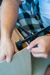 The carpenter uses the f-clamp to assemble the wooden box.
