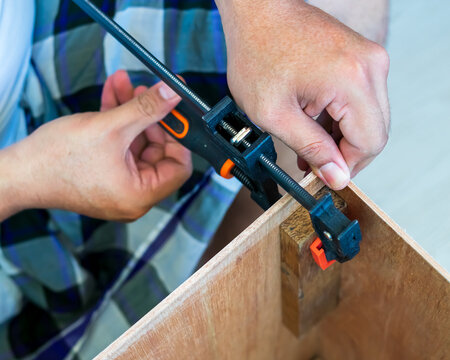 The carpenter uses the f-clamp to assemble the wooden box.