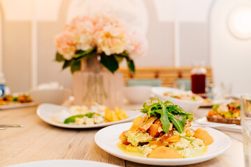 serving table with bouquet of pink flowers, appetizers and salads for holiday. 