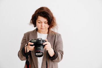 brunette woman in checkered jacket looks at pictures on camera display 