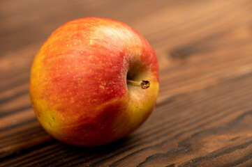 A fresh red apple on a rustic wooden table.