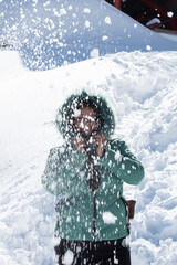 Fototapeta na wymiar Beautiful woman in warm hooded jacket having fun on snowcapped mountain with powder snow