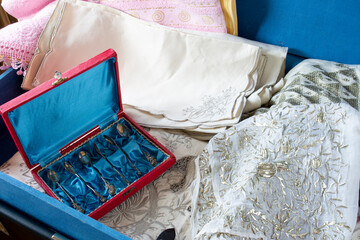 Fototapeta na wymiar Old fashioned Turkish style dowry in a blue dowry chest. antique spoons, plates, embroidered towels, embroidered muslin and lace. Selective Focus Lace and spoons.
