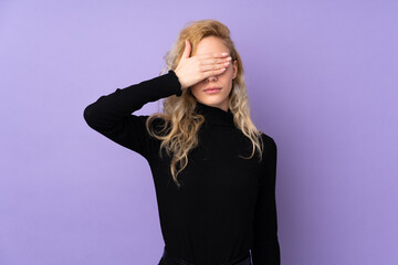 Young blonde woman isolated on purple background covering eyes by hands. Do not want to see something