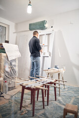 Young adult man painting on a DIY budget renovation of his new home apartment.