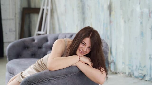A woman lies on the couch and poses for a photo shoot in a photo studio loft.