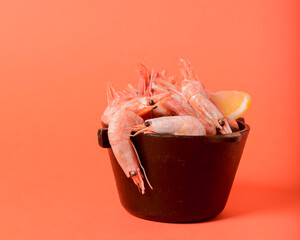 Shrimps with lemon and fresh dill in a small black bowl over colorful background. Sea food, healthy...