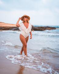 Fototapeta na wymiar Lifestyle of a blonde Caucasian girl in a white swimsuit enjoying the summer. Enjoying on the seashore