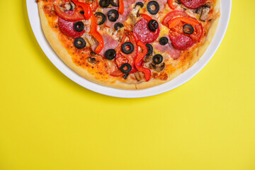 A whole, cooked and sliced peperoni pizza on a colorful backgroud, various colors. Copy space banner.