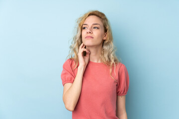 Young blonde woman isolated on blue background thinking an idea