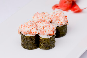 An Image of Sushi rolls set with caviar on a white plate over white background.