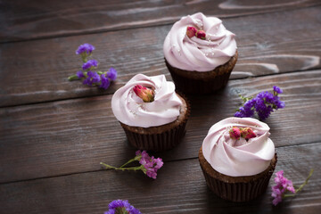 Cupcakes with dried roses, brown wooden board. Cupcakes with roses