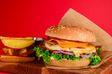 Bacon and beef patty burger with red onions and cheese over red background. Fast food, junk food concept.