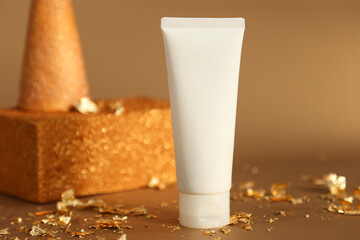 Mockup of white squeeze bottle plastic tube for branding of medicine or cosmetics - cream, gel, skin care. Cosmetic bottle container, gold cone on gold rectangular podium on golden background.