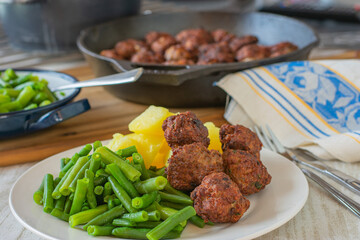 Meatball dinner with green beans and potatoes served on a plate