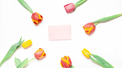 card for copy text next to a bouquet of tulip flowers on natural white background from above. Spring bud bouquet creative frame design.