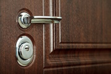Metal door handle and door with chrome handle, lock. Use your keys to lock brown textured door. Keyhole and doorknob close-up. Concept of locked doors for design apartment or office. Copy space site