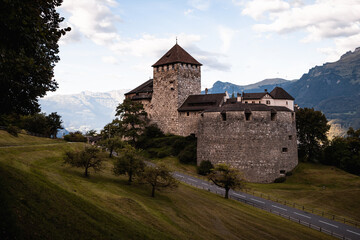 Fototapeta na wymiar Sunrise at Castle Vaduz with curved road, blue sky and green forest (Vaduz, Principality of Liechtenstein, Europe)
