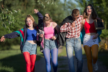 A man with a cassette tape recorder and beautiful girls dressed in the style of the nineties.