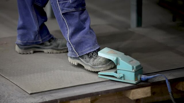 Manufacturing of construction fittings. Close-up. The worker's foot presses the pedal of the argon welding machine.