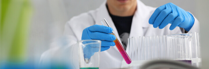 A male chemist holds test tube of glass in his hand overflows a liquid solution