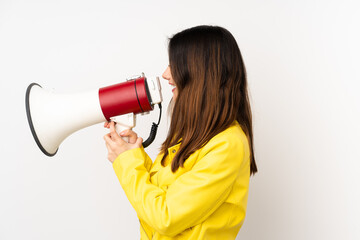 Young caucasian woman isolated on white background shouting through a megaphone