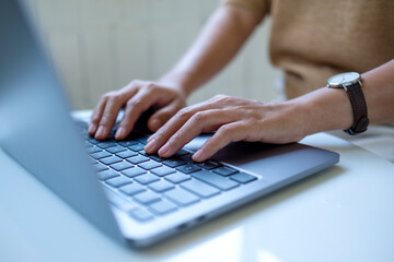 Closeup image of a woman working and typing on laptop computer keyboard on the table