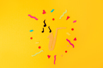 Festival and holiday. A cutted out of felt saxophone on a yellow background. Flat lay. International Jazz Day