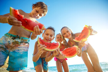 Children play by the sea and eat watermelon. High quality photo.