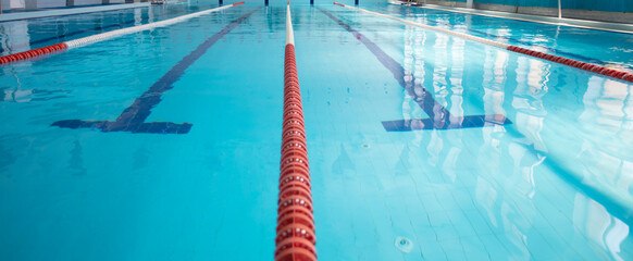 Obraz premium An empty sports pool with a red dividing path. Blue water in the swimming pool.