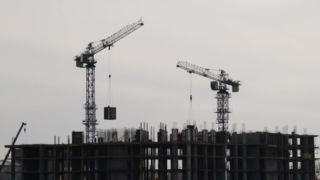 Silhouettes of construction cranes working