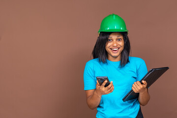 beautiful female african contractor smiling and feeling excited while holding her phone, she looks like she has been pleasantly surprised