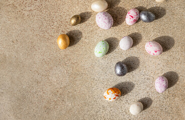 Fototapeta na wymiar Multicolored candies shaped eggs on a light concrete background. Happy Easter holiday. Minimalism concept. Top view. Copy space.