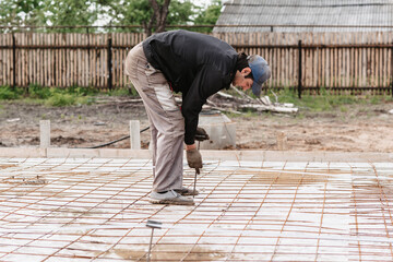 male construction worker prepares rebar for the foundation of the construction of a house