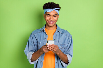 Photo portrait of handsome guy reading information on mobile phone smiling isolated vivid green color background
