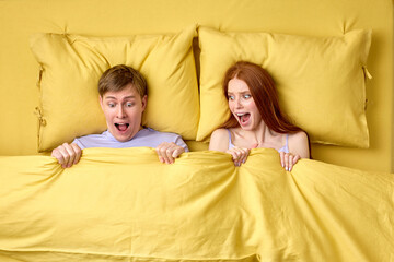Surprised caucasian lovers embarrassed and frightened, shocked looking at male genital