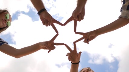 A group of friends make a star shape out of their fingers.