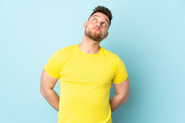 Russian handsome man isolated on blue background and looking up