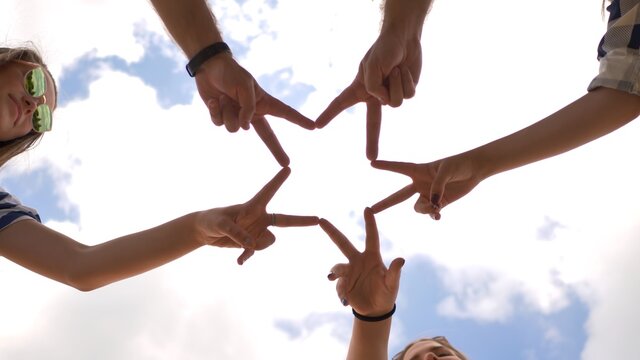 A Group Of Friends Make A Star Shape Out Of Their Fingers.