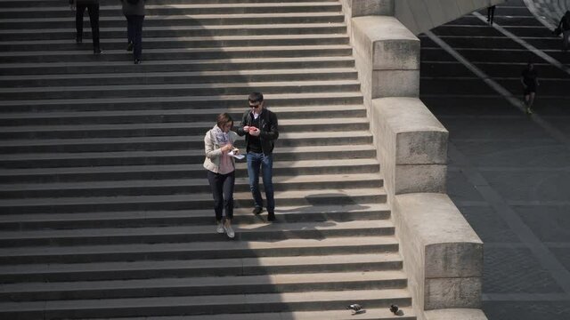 Boyfriend feeds beloved woman going down large old steps