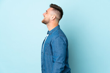 Fototapeta premium Russian handsome man isolated on blue background laughing in lateral position