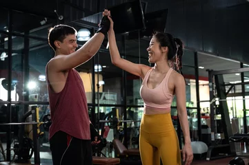  Cheerful young man and woman giving high five after a successful workout session in a modern fitness club  © think4photop